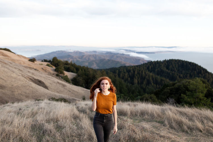 Full length of young woman standing on mountain