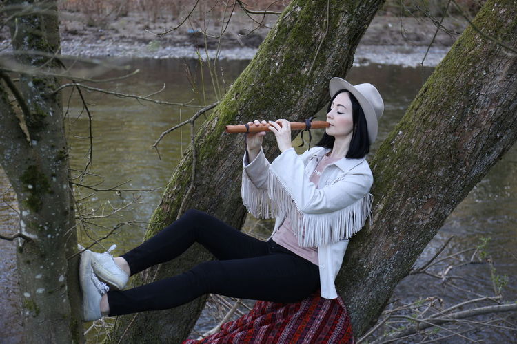 Woman playing flute on tree