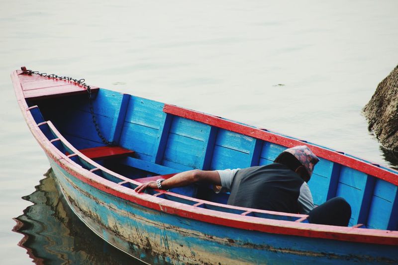 Rear view of man sitting in boat on sea