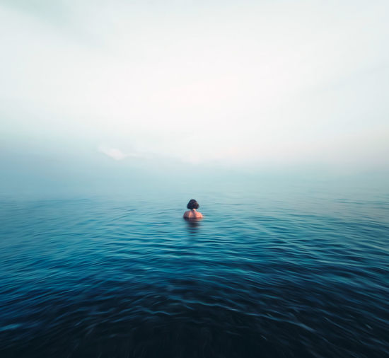 Man swimming in sea against sky