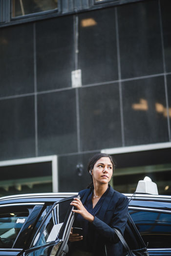 Female entrepreneur looking away while coming out from car