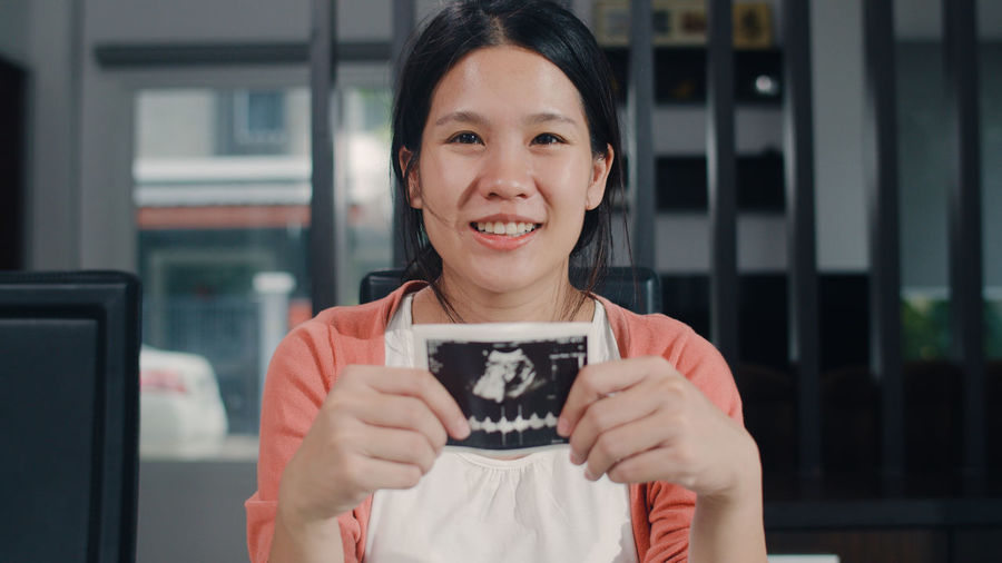 Portrait of smiling pregnant woman holding ultrasound