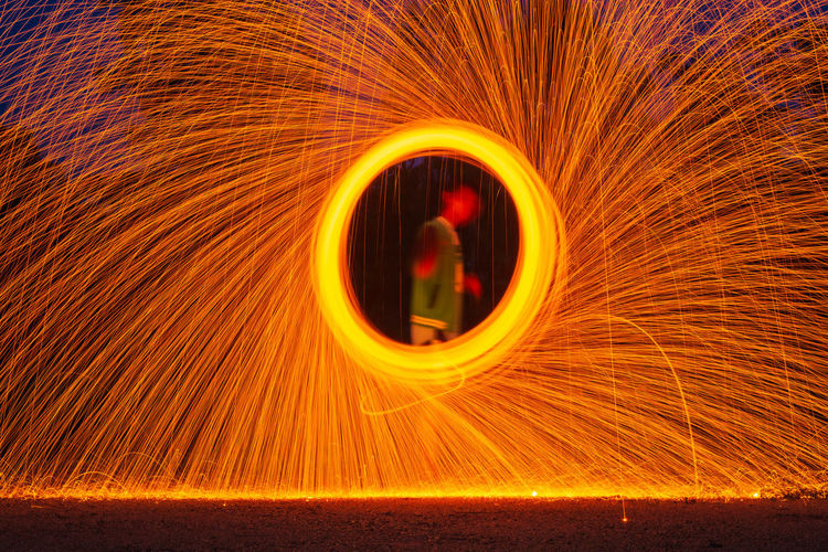 Blurred motion of man against illuminated fire at night