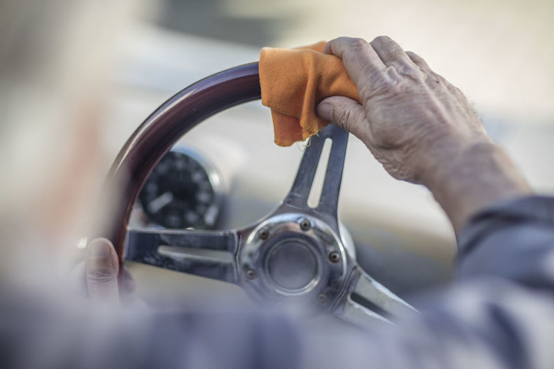 Senior man polishing steering wheel of a car