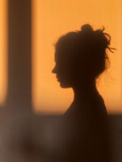 Rear view of silhouette woman against orange wall