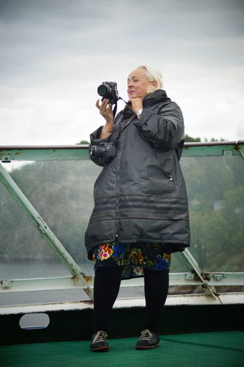 Full length of woman photographing against sky