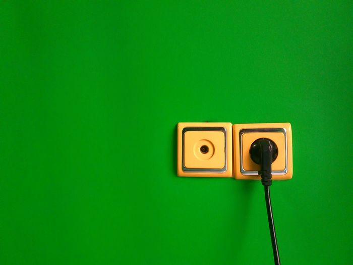 Close-up of electric plug on green wall