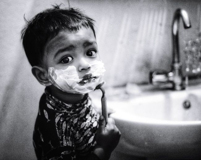 Portrait of cute baby boy shaving in bathroom 