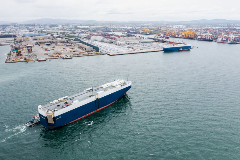Roll-on roll-of ship loading new cars line up . automotive container carriers floating in sea, 