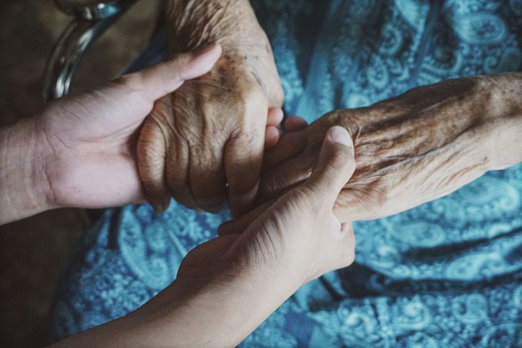 Cropped image of person holding senior woman hands