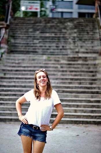 Portrait of smiling woman standing against steps