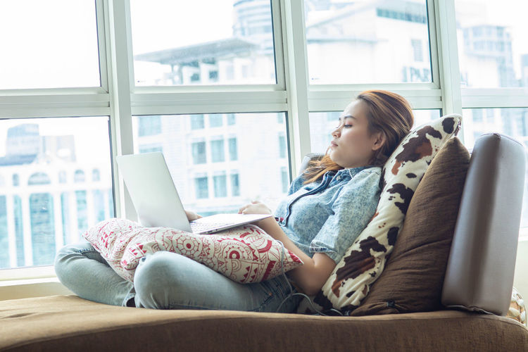 Side view of woman sitting on sofa at home