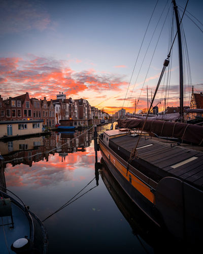 Sailboats moored at harbor against sky during sunset
