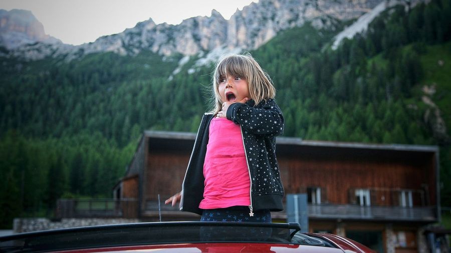 Shocked girl standing in car against mountains