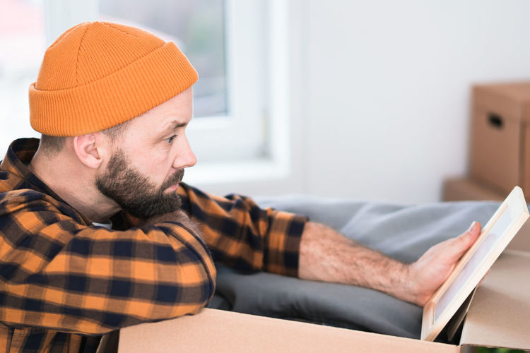 Side view of man using laptop while sitting on sofa at home