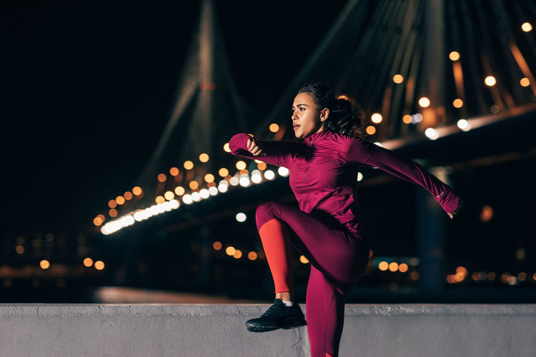 Woman exercising in city at night