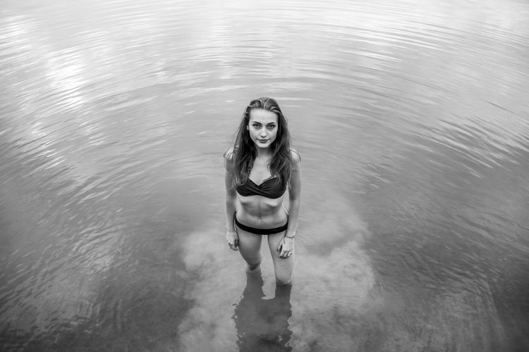 High angle portrait of young woman wearing bikini standing in lake