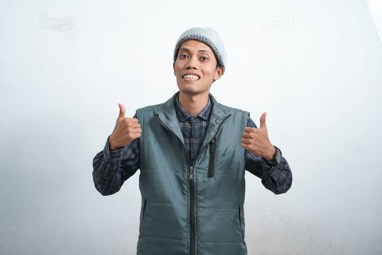 Portrait of young man standing against white background