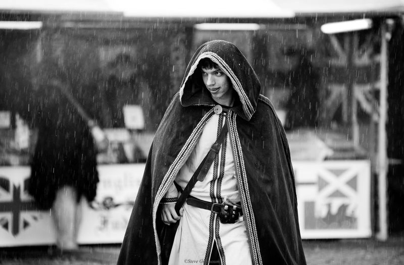 Young man wearing cape while standing outdoors during rainfall
