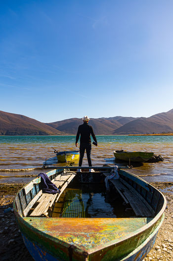 Rear view of man standing on shore against sky