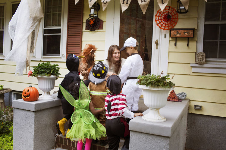 Woman talking to children in halloween costumes during trick or treating