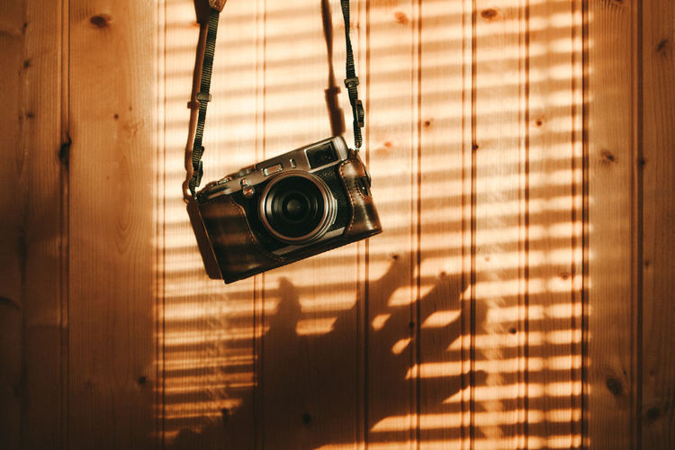 Close-up of camera hanging against wood