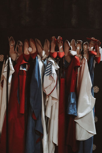 Different fashion outfits and high heels shoes hanging in a row at the backstage area. 