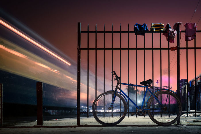 Blurred train with parked bicycle against the gate