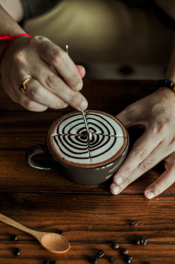 Midsection of woman holding coffee cup on table