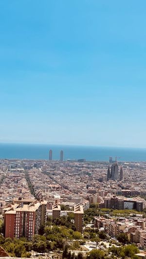 Aerial view of buildings and sea against clear blue sky