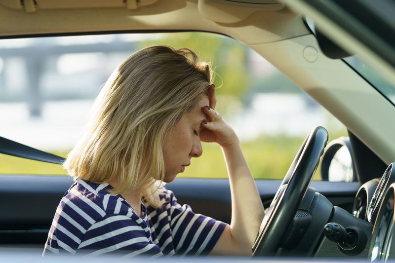 Depressed woman sit in car pondering of problems in family, relationship crisis, burnout and stress