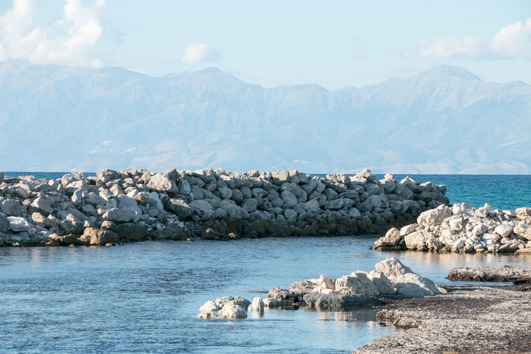 Scenic view of sea by mountains against sky