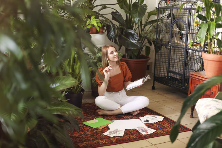Woman sitting by potted plants