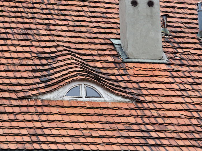 Red roof made of tiles with loftop window and chimney