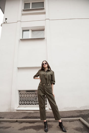 Female fashion model, posing for a full length photo, wearing green suit, urban fashion photography