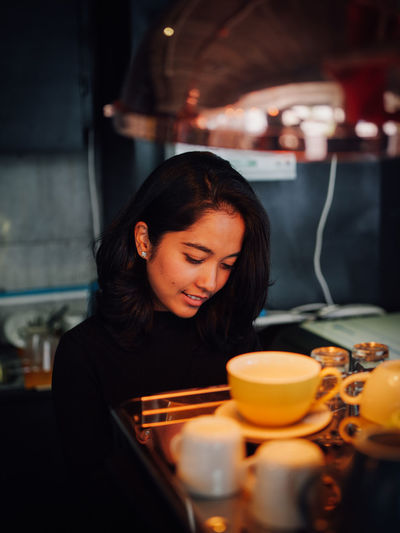YOUNG WOMAN SMILING WITH DRINK ON TABLE