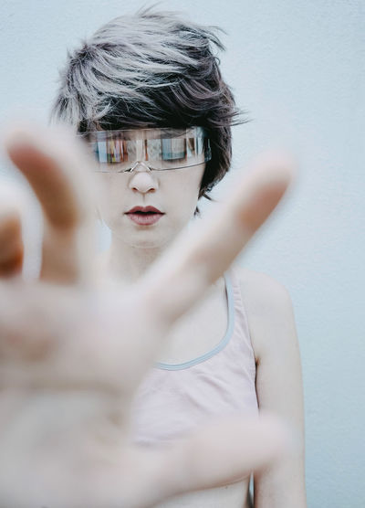 Woman gesturing wearing smart glasses against white background