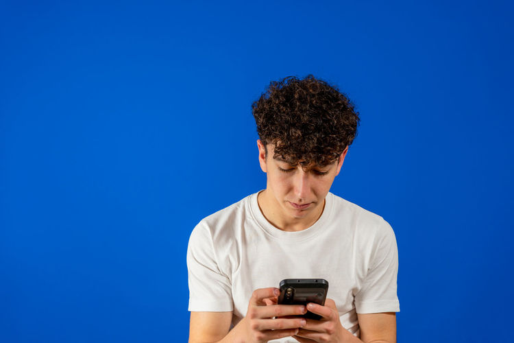 Man using smart phone against blue background