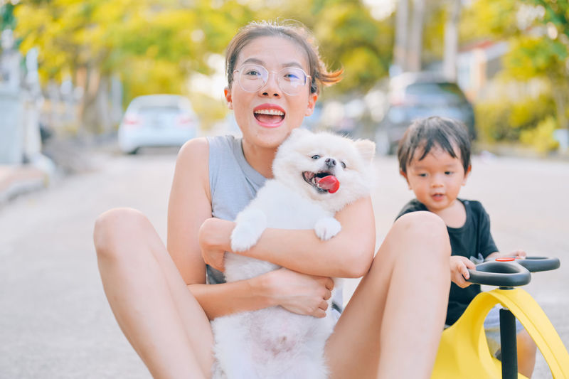 Portrait of smiling woman with dog sitting outdoors