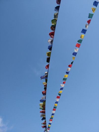 Low angle view of prayer flags against sky on sunny day