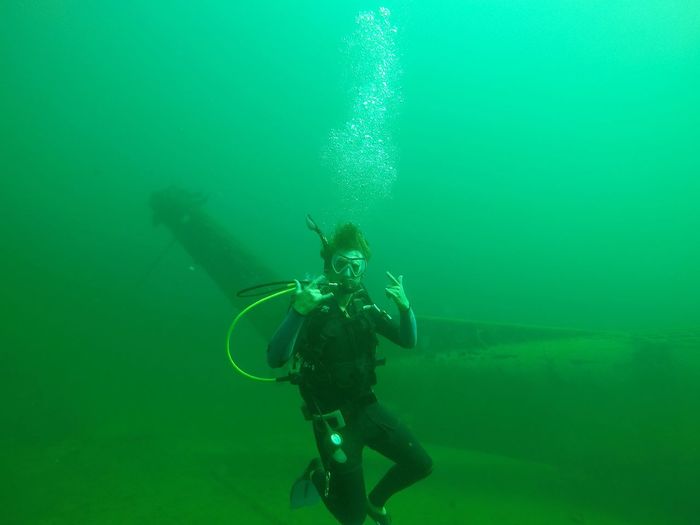 Man swimming against airplane wreckage undersea