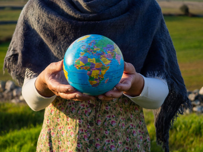 Midsection of woman holding globe while standing outdoors