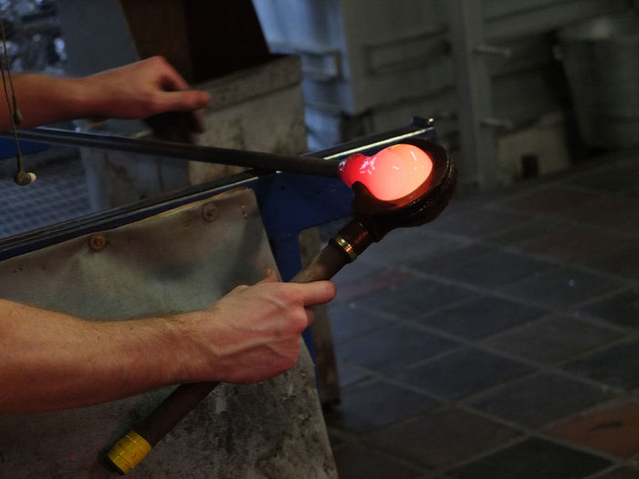 Cropped hands of man blowing glass at workshop