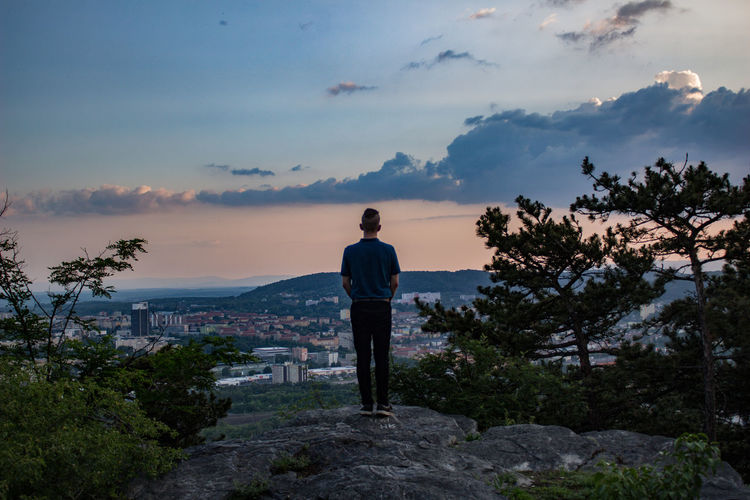 Rear view of man standing on mountain against sky