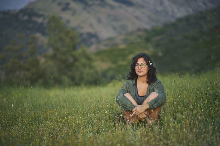 Portrait of a young woman sitting in a meadow at sunset. the sun illuminates her face.