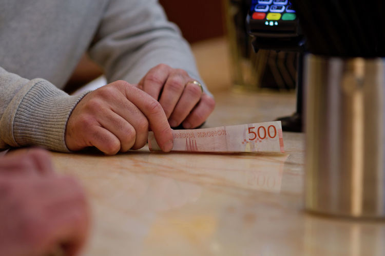 Midsection of woman holding paper currency at table
