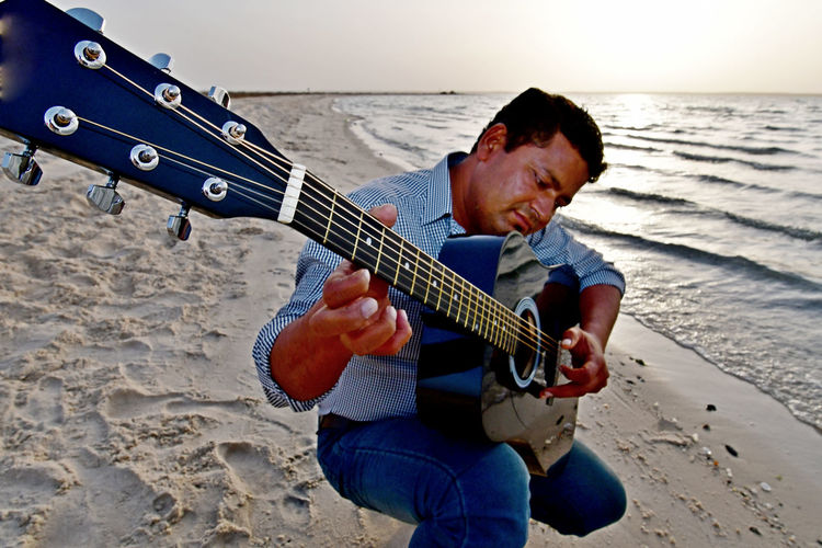 Man playing guitar at beach