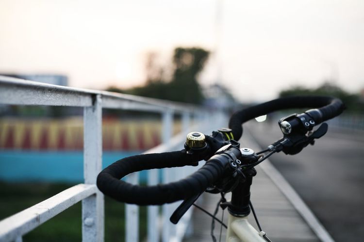 Close-up of bicycle on railing against sky