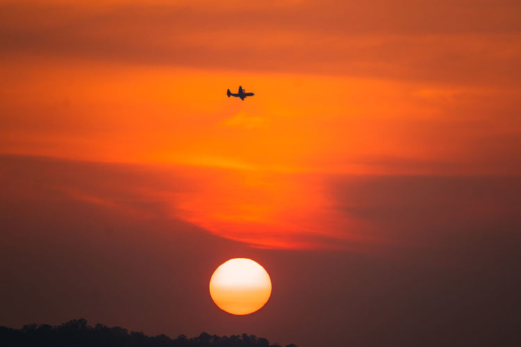 Airplane in sky at sunset