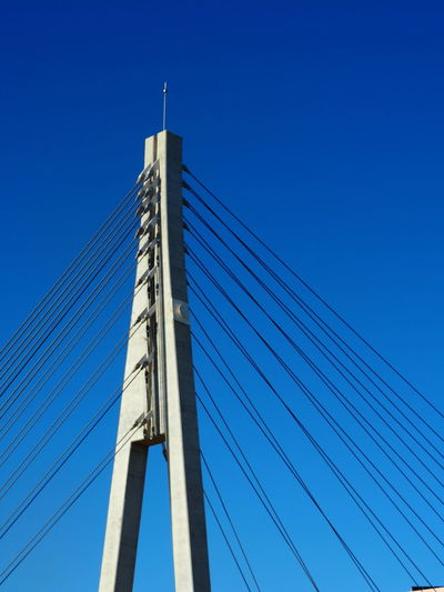 Low angle view of suspension bridge against clear blue sky
